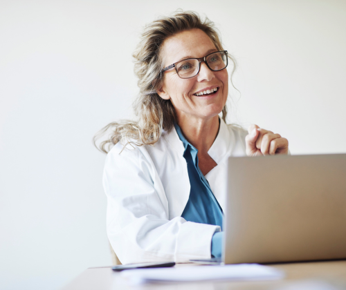 Woman in glasses leans against an office wall.