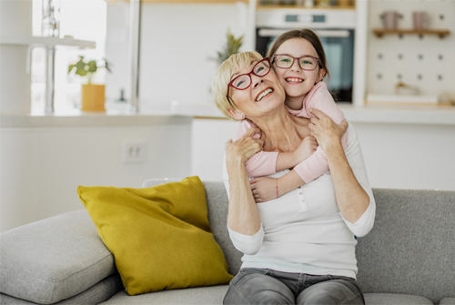 Granddaughter hugs her grandma both wearing glasses showing vision care at different stages of life 